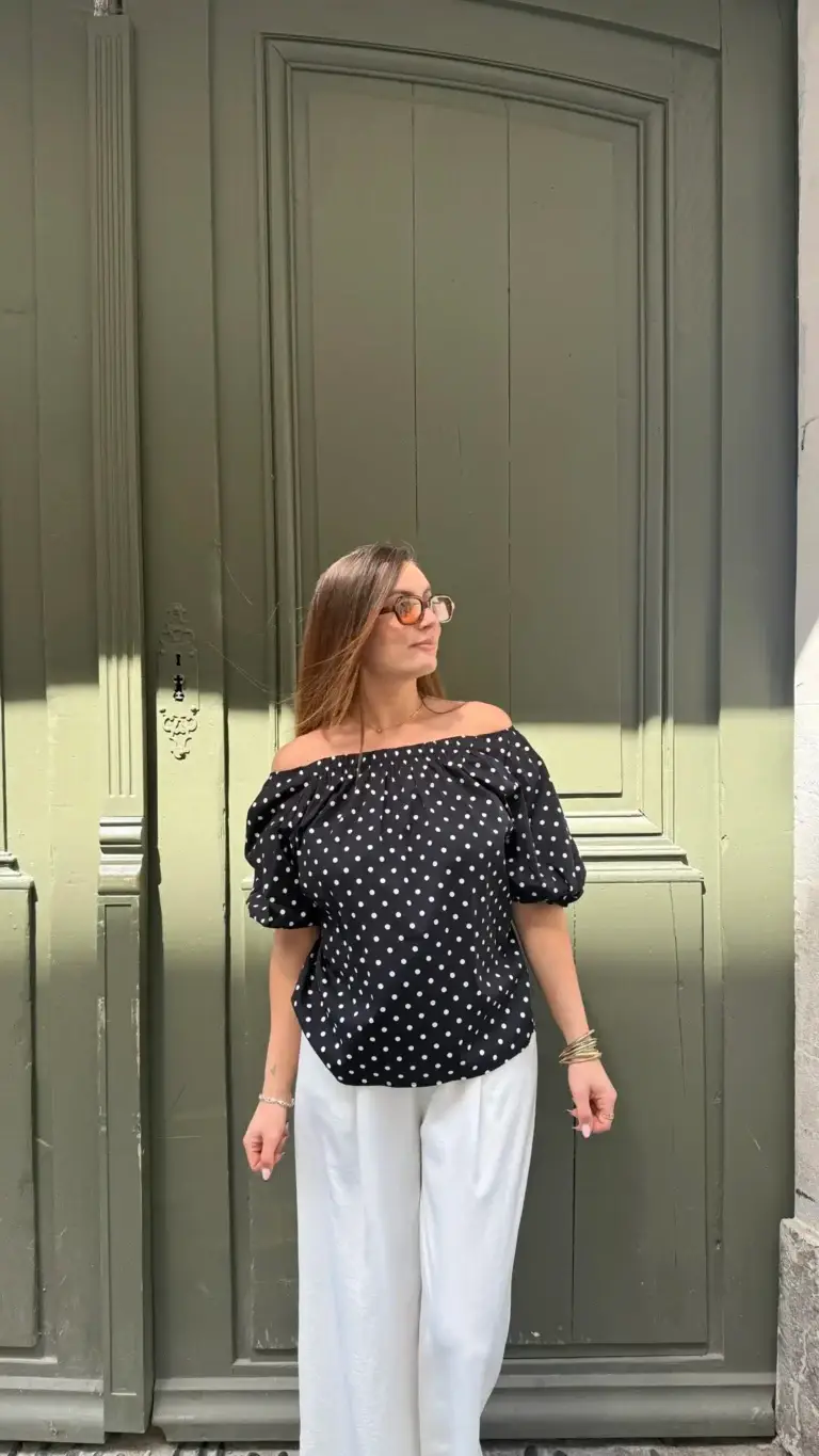Blouse Ava à pois avec ouverture dans le dos nouée, disponible en blanc ou noir, portée par Clémence et Lucie